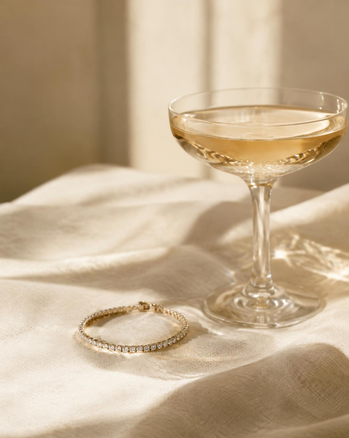 Champagne and a diamond bracelet resting on sunlit linen